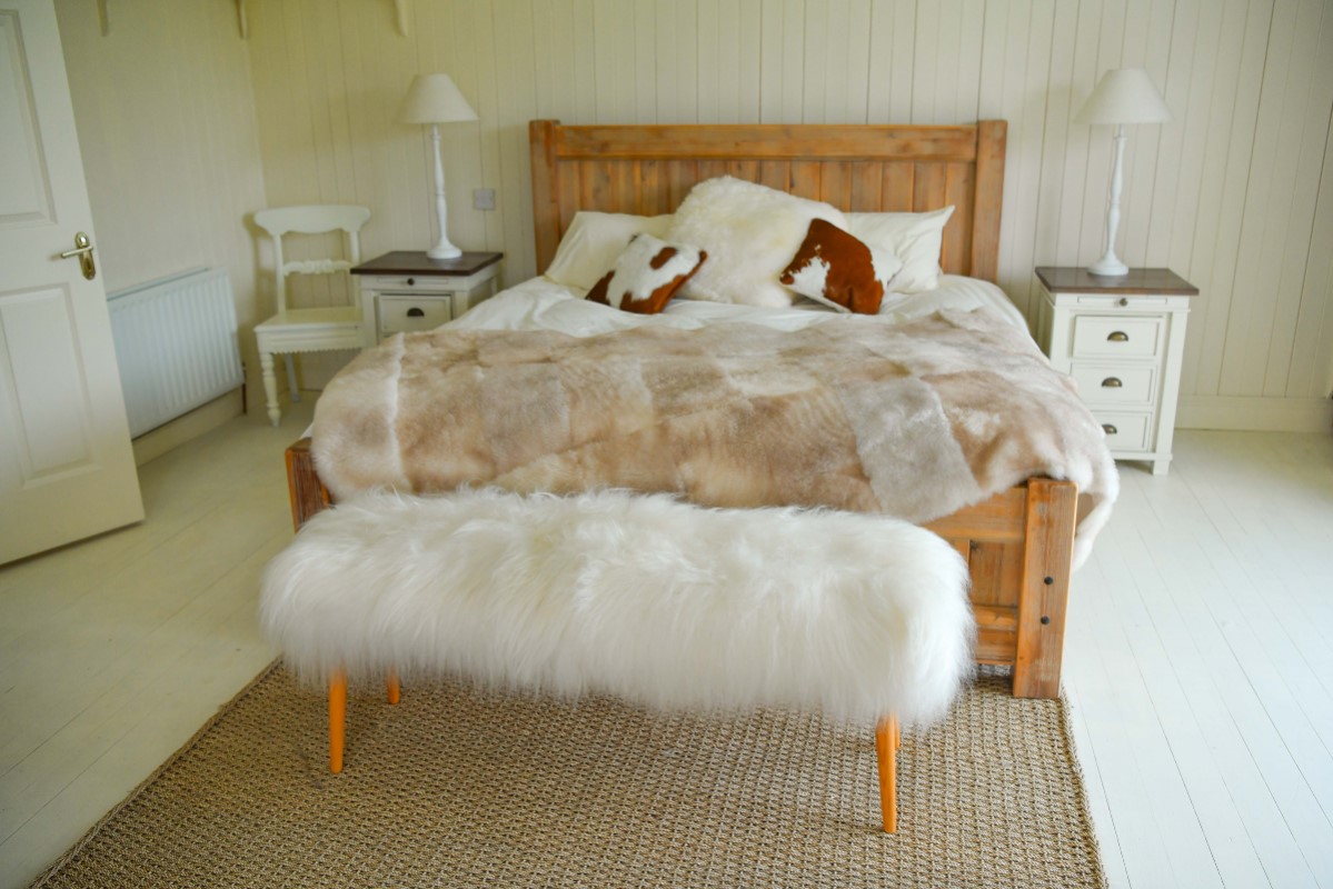 ławeczka oraz piękna narzuta na łóżko wykonane ze skór owczych